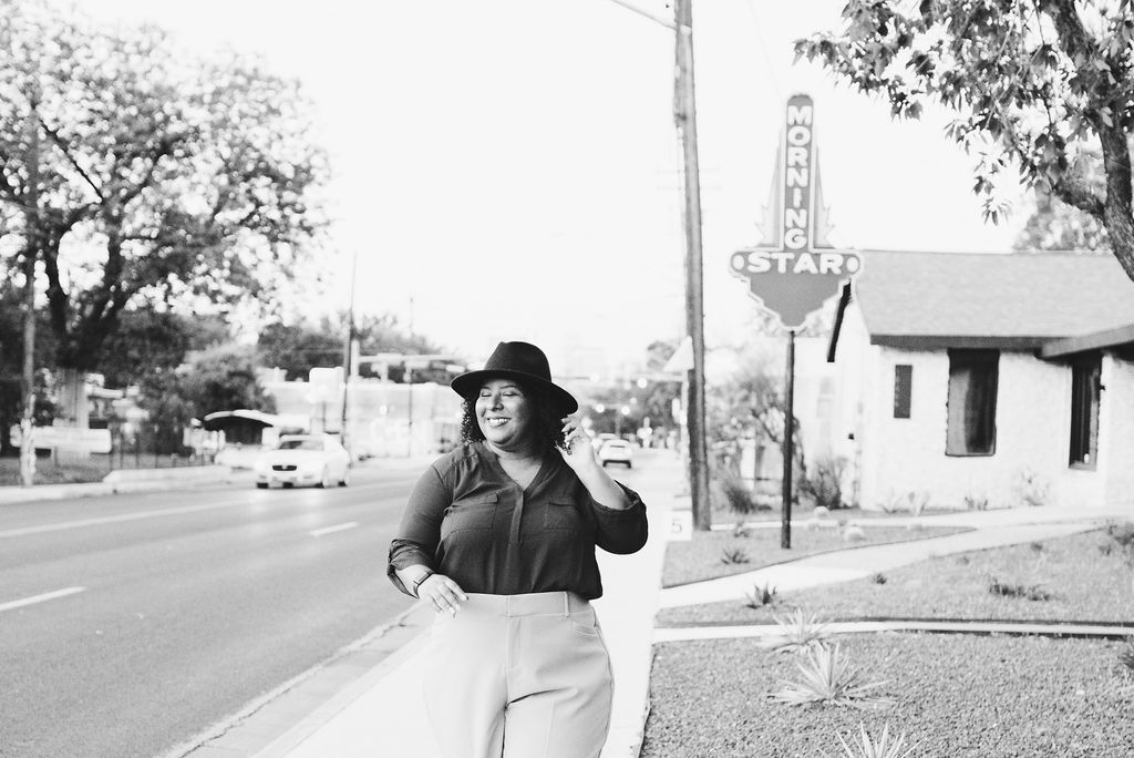 Woman with a hat standing on a sidewalk in front of a building on South First St. in Austin, Texas.
