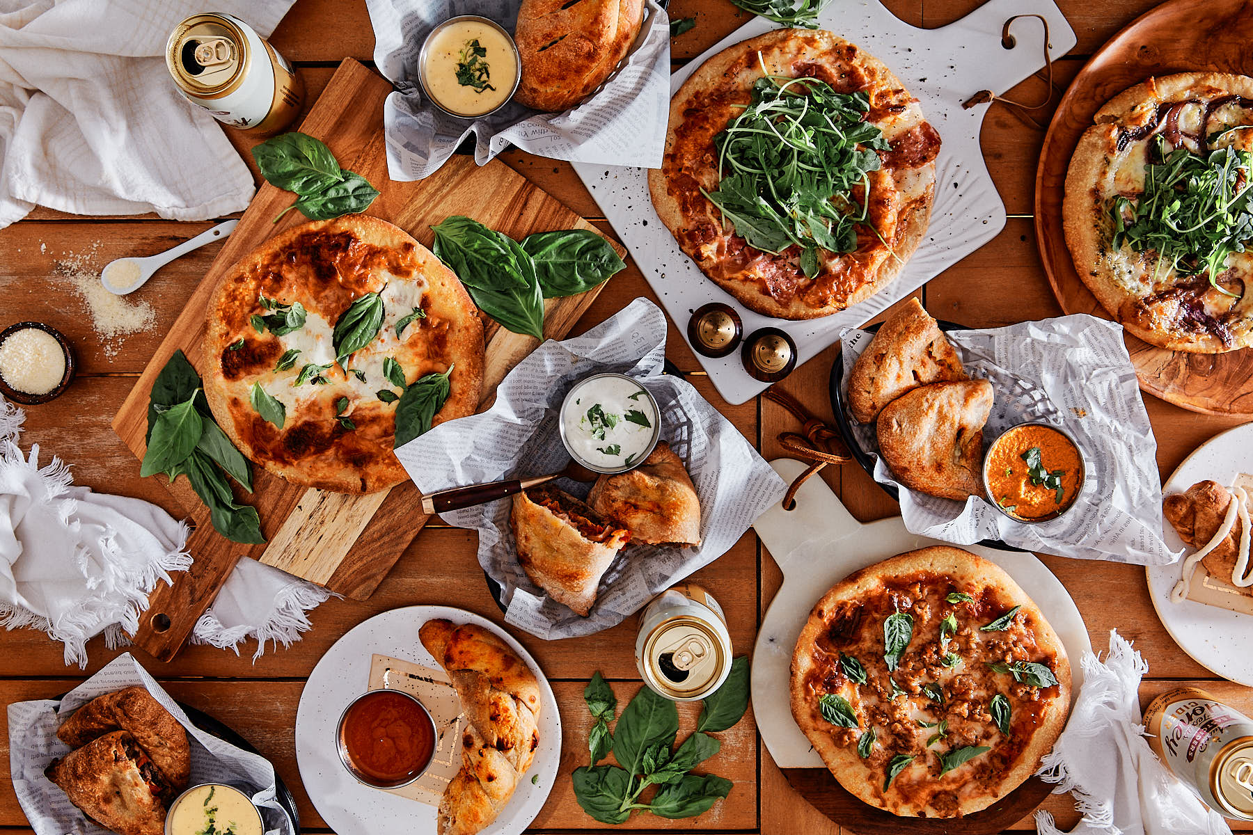 A flat lay of pizzas and calzones