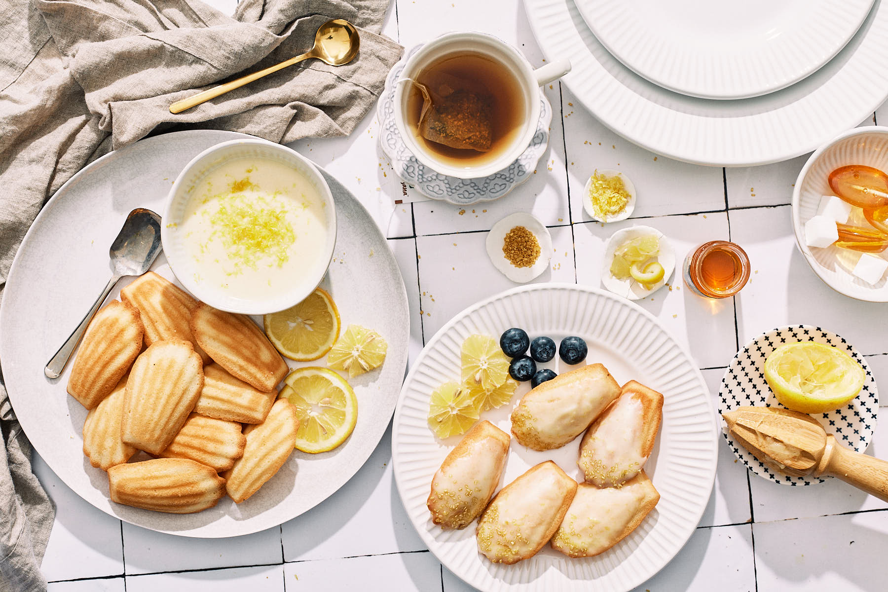Flat lay image of madeleine's on a plate with a cup of tea.
