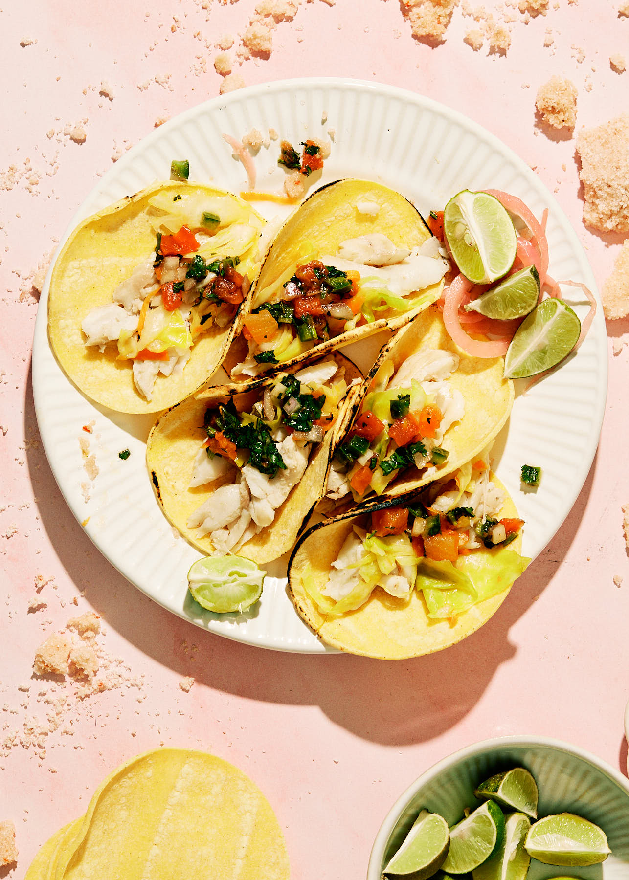 Tacos on a white plate with a pink background