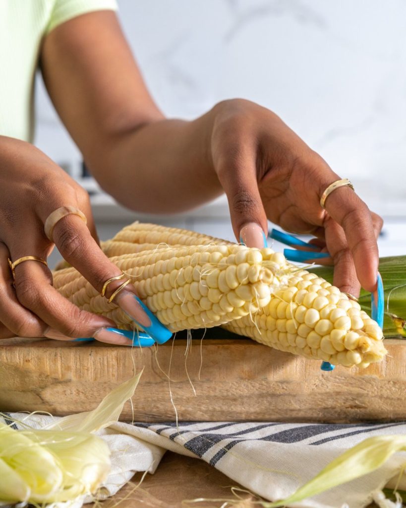 african american hands holding shucks of corn