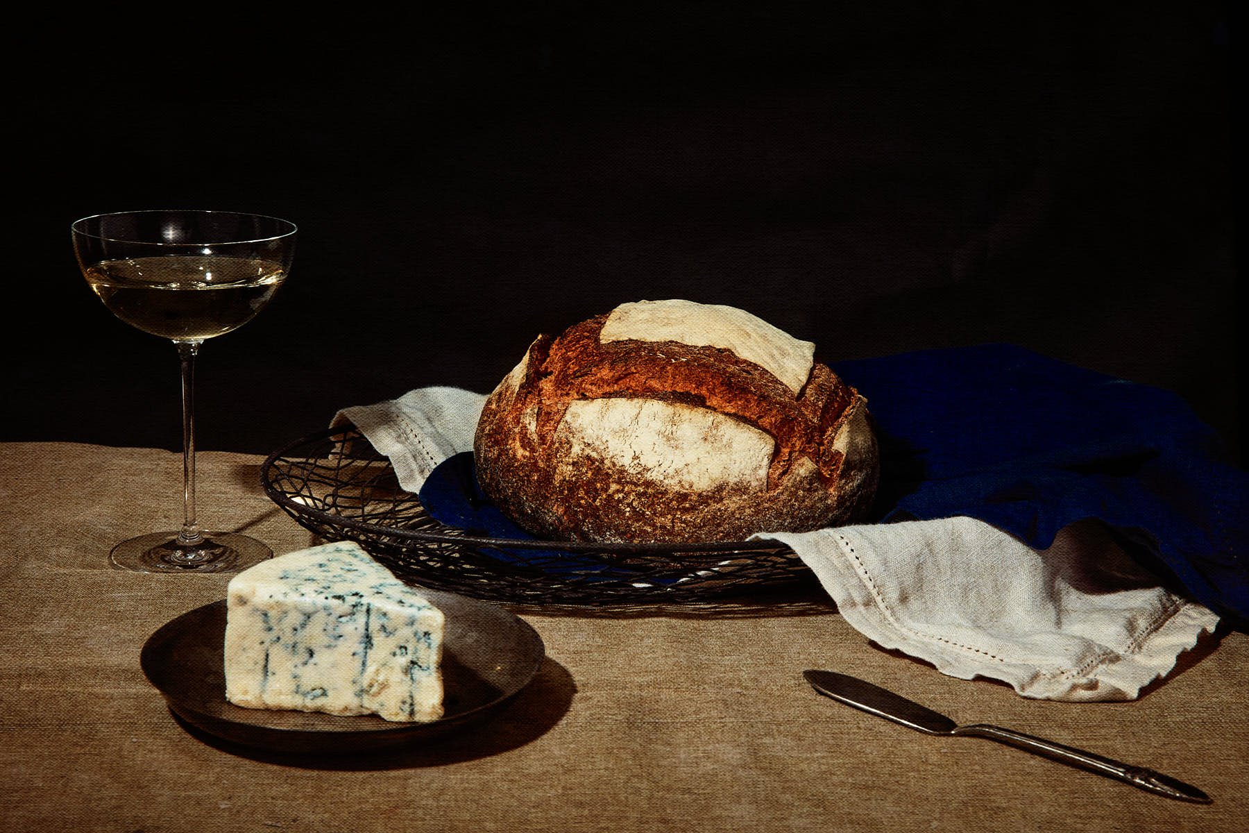 photo of bread, blue cheese, wine glass on a table