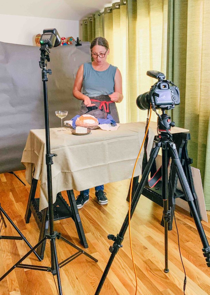 woman standing behind table with camera pointing at her