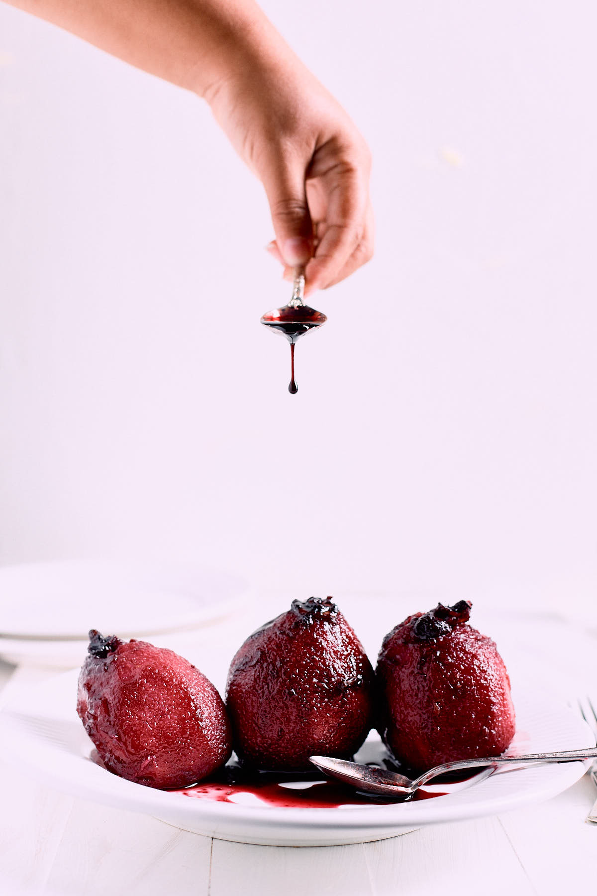 hand pouring juice on poached pears
